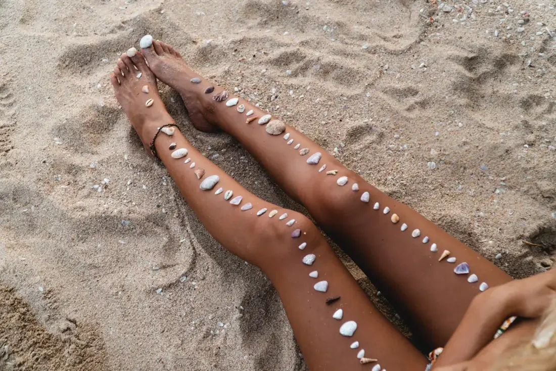 Jambes dorées sur le sable, coquillages